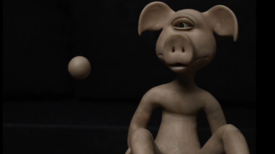 A one-eyed pig creature sits in the dark beside a small floating clay sphere.